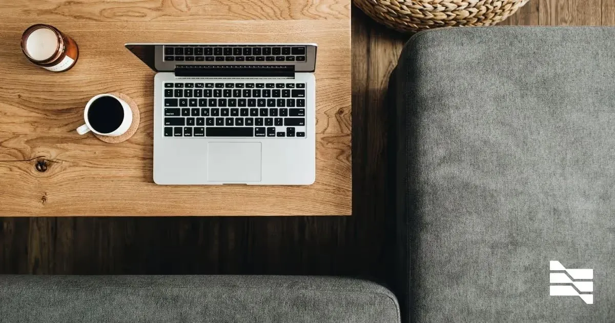 Top-down view of a freelancer's wooden work desk with an open laptop, coffee mug, and candle, epitomizing essential web development tools.